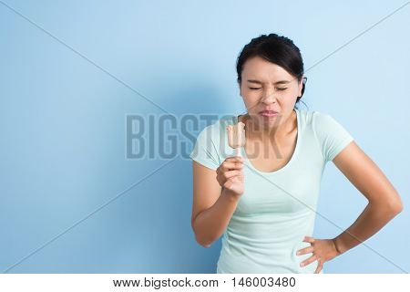 Asian young woman with hypersensitive teeth eating ice lolly, closeup portrait with copyspace
