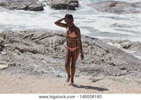 Image of a gorgeous african bikini model with braids walking on the beach with copyspace