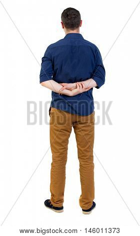 Back view of man . Standing young guy. man in a blue shirt with the sleeves rolled up, standing with hands clasped behind his back.