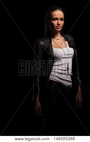 sexy woman in leather jacket and undershirt standing on black background