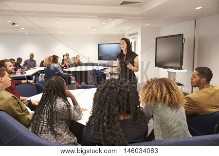Female teacher addressing university students in a classroom