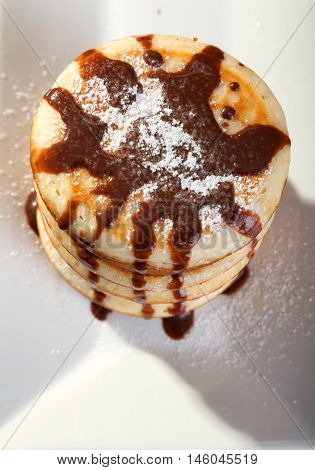 American pancakes with chocolate syrup and caster sugar.
