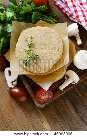 Fresh raw chicken cutlets with herbs and vegetables on a wooden board