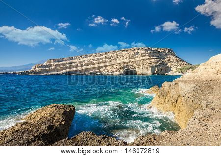 Matala beach on Crete island, Greece. Tourists relax and bath in crystal clear water of Matala in south of Creta. There are many caves near the beach.