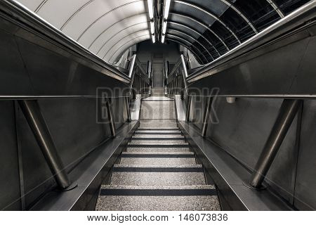 Stairwell descending to a dim and gloomy underground tunnel