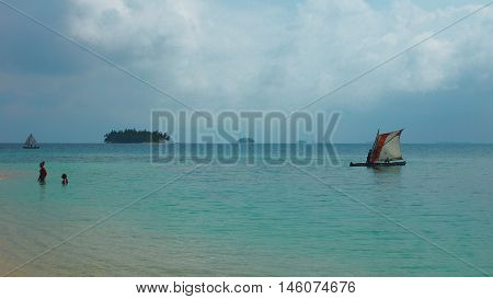 Small sailboat sailing close to the beach of Aguja Island, Las perlas / Panama