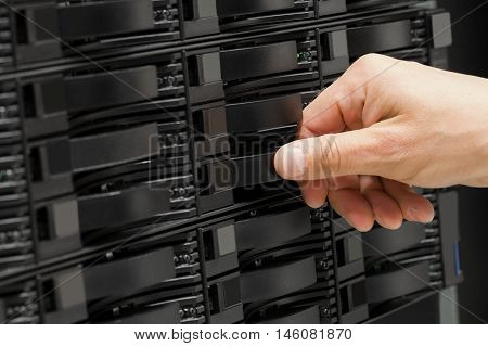 IT technician or engineer working with hard drives in a storage array network. Data backup in a large datacenter.