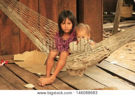 KOH RONG SAMLON, CAMBODIA - DECEMBER 13: Unidentified kids sit in a hammock on December 13, 2011 on Koh Rong Samlon island, Cambodia. Koh Rong Samlon has local village and a resort for tourists