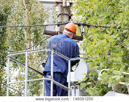 Electrical worker repairing the wires on the pole with the help of the lift car