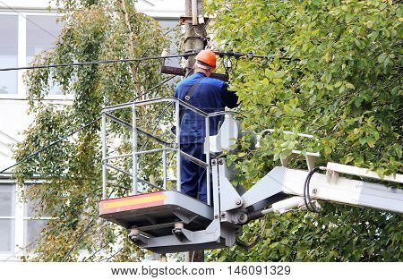 Electrical worker repairing the wires on the pole with the help of the lift car