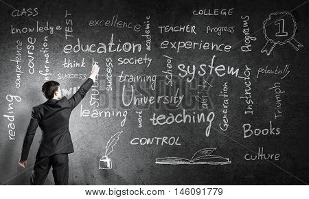 Rear view of man drawing education concept on blackboard with chalk