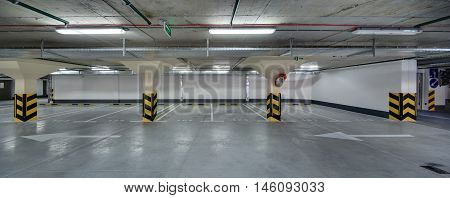 Underground parking without cars. Floor with white markings for drivers. Columns painted in bright yellow stripes.