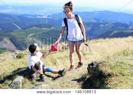 Summer adventure expedition in the mountains. Girl gives the boy a first aid kit.