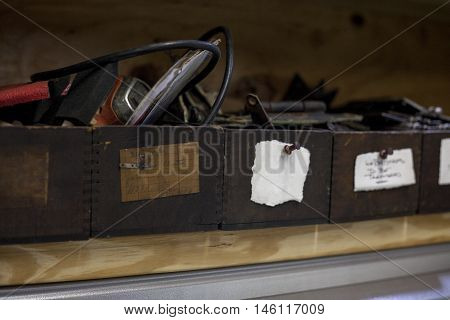 Antique boxes sit on shelf with various items inside with one label left blank.