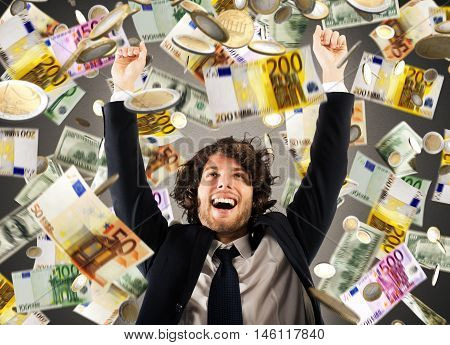 Happy businessman exults under a rain of coins and banknotes