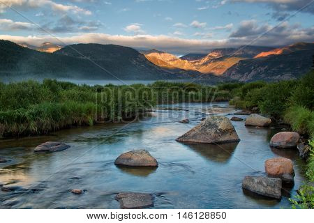 A layer of fog sweeps in over Moraine Park and the Big Thompson River on a summer morning. The beautiful continental divide mountains light up in the morning sun