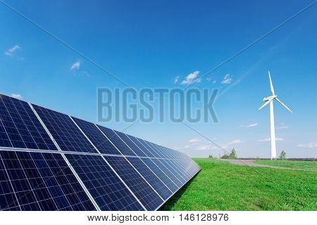 Windmill And Solar Panels On Blue Sky At Daytime