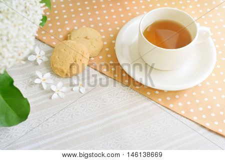 The Time of Tea Break on the table top view. Polka dot tablecloth with cup, cookies and white flower with copy space