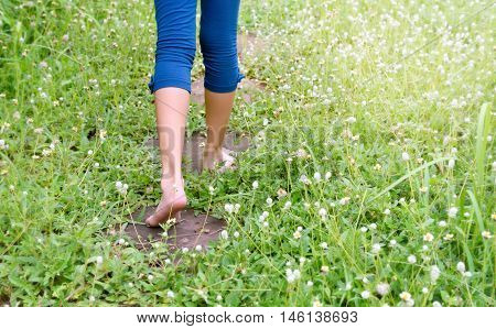 Bare feet of a kid walking on rock garden in the rainy season, through a green field and flower of grass, copy space, back to nature, back to nature