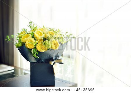 beautiful yellow English roses flower bouquet on wooden table next to window with sun light, copy space