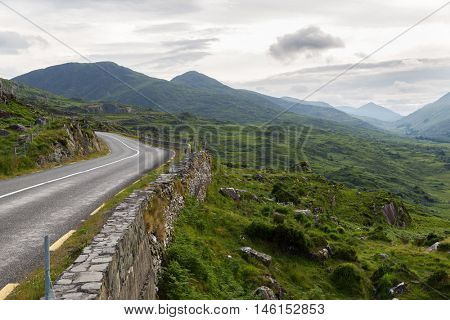 travel, trip and countryside concept - view to asphalt road and rocky hills at connemara in ireland