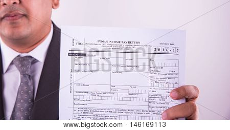 indian businessman showing indian income tax return form or ITR-4 form or form no. 16 of income tax department of india, selective focus