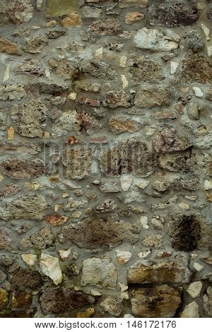 Stone wall of natural brown gray rocks rough surface facade outdoors on masonry background