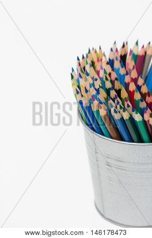 Various colour pencils organized in a can. Stack of colored pencils in a tin can on white background.