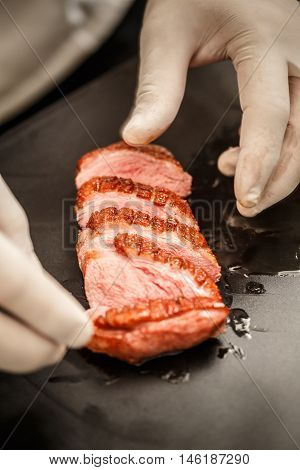 Chef arranged roasted goose breast slice on black