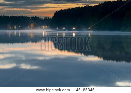 Night bridge with the lights at the lake in the fog