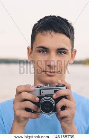 Cute boy teenager with vintage rangefinder camera. Close-up Photo.