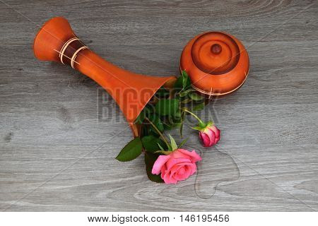 Capsize flower vase with roses. The vase is a wooden base. Water leaked out of a vase.