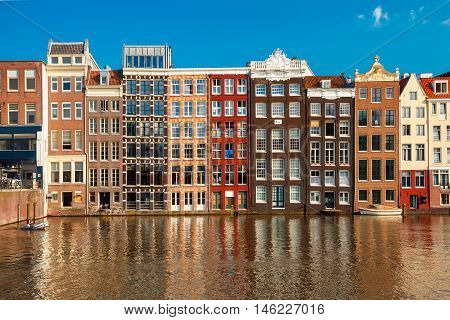 Beautiful typical Dutch dancing houses at the Amsterdam canal Damrak in sunny day, Holland, Netherlands.
