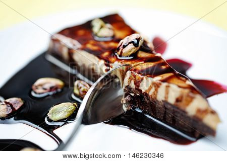 Slice of Chocolate cake with Pistachio, extreme selective focus - focus on teaspoon digging into the cake and Pistachio bean, horizontal