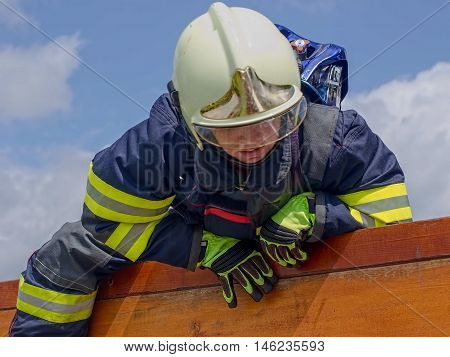 Firefighter with the oxygen tank and the helmet.Climb A vertical wall at obstacle race.Contest TFA - Toughest Firefighter Alive.