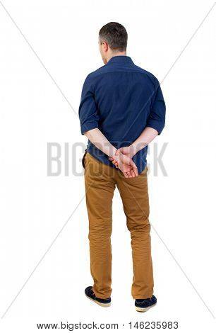 Back view of man . Standing young guy. man in a blue shirt with the sleeves rolled up is looking pensively into the distance.