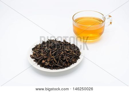 Clear glass of tea and dry tea leaves in a cup isolated on white background.
