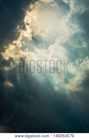 Sunlight rays in dramatic pre-thunderstorm sky forming man's face profile view.
