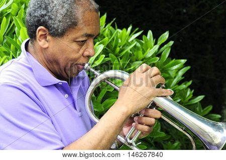 African american male with his flugelhorn outside.