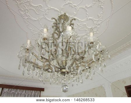 many-tier chandelier on a ceiling of a drawing room the decorated stucco molding