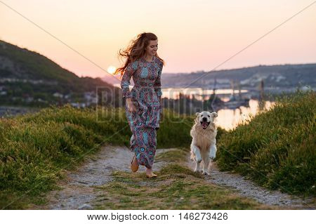 Beauty woman with her dog playing outdoors.