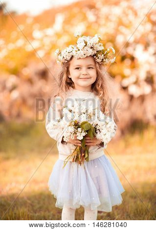 Cute stylish girl holding flowers outdoors over nature background. Looking at camera.