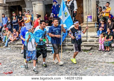 Antigua Guatemala - September 14 2015: Locals run in streets with Guatemalan flags & lit torches while blowing whistles during Guatemalan Independence Day celebrations