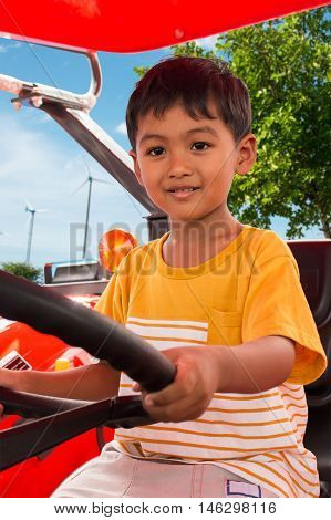 Cute little boy drive tractor on natural background