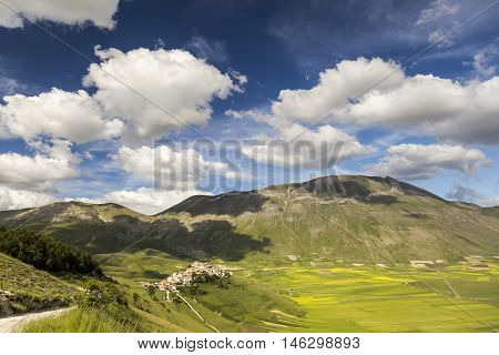 Famous mountain village of Castelluccio di Norcia with beautiful summer landscape at Piano Grande (Great Plain) mountain plateau in the Apennine Mountains on a sunny day, Umbria, Italy