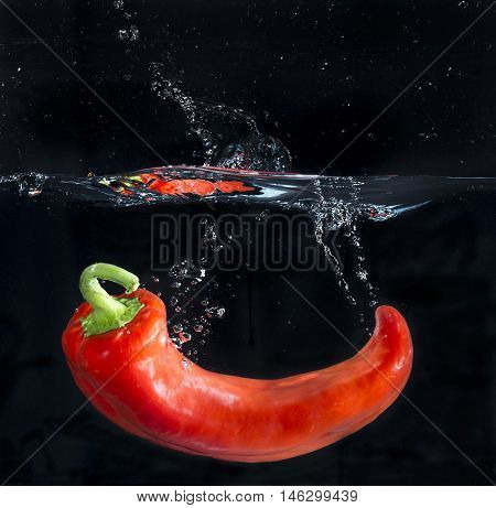 Red pepper splashing in the water with bubbles