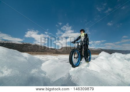 Fatbike (also called fat bike or fat-tire bike) - Cycling on large wheels. A cyclist sits on the bike on the ice.