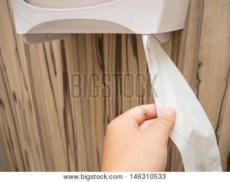 Pulling tissue paper in a public toilet