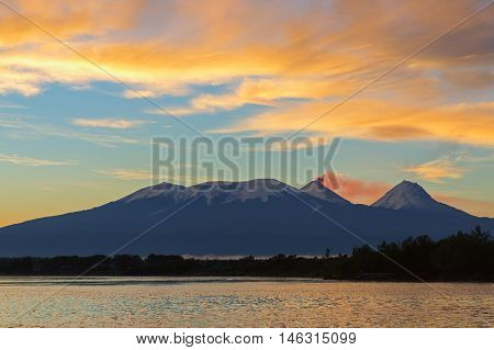 Beautiful sunrise over the volcanoes Kluchevskaya group with reflection in the river Kamchatka.
