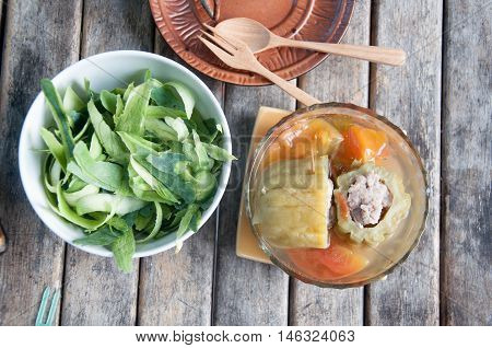 Stuffed bitter gourd with minced pork in clear soup on wood table